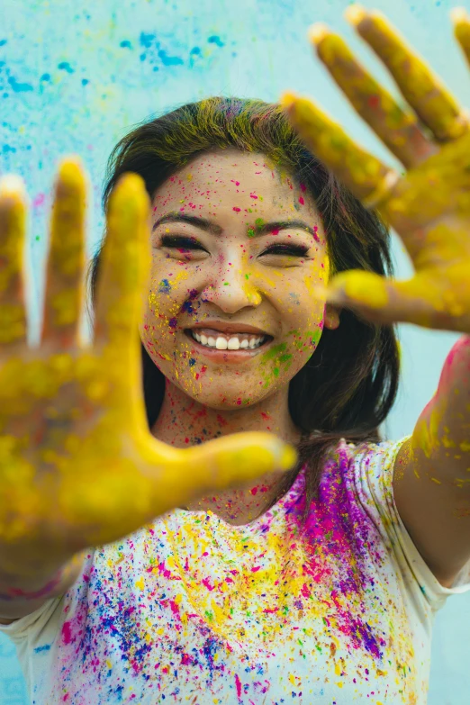 a woman in a white shirt is covered in bright colored powder