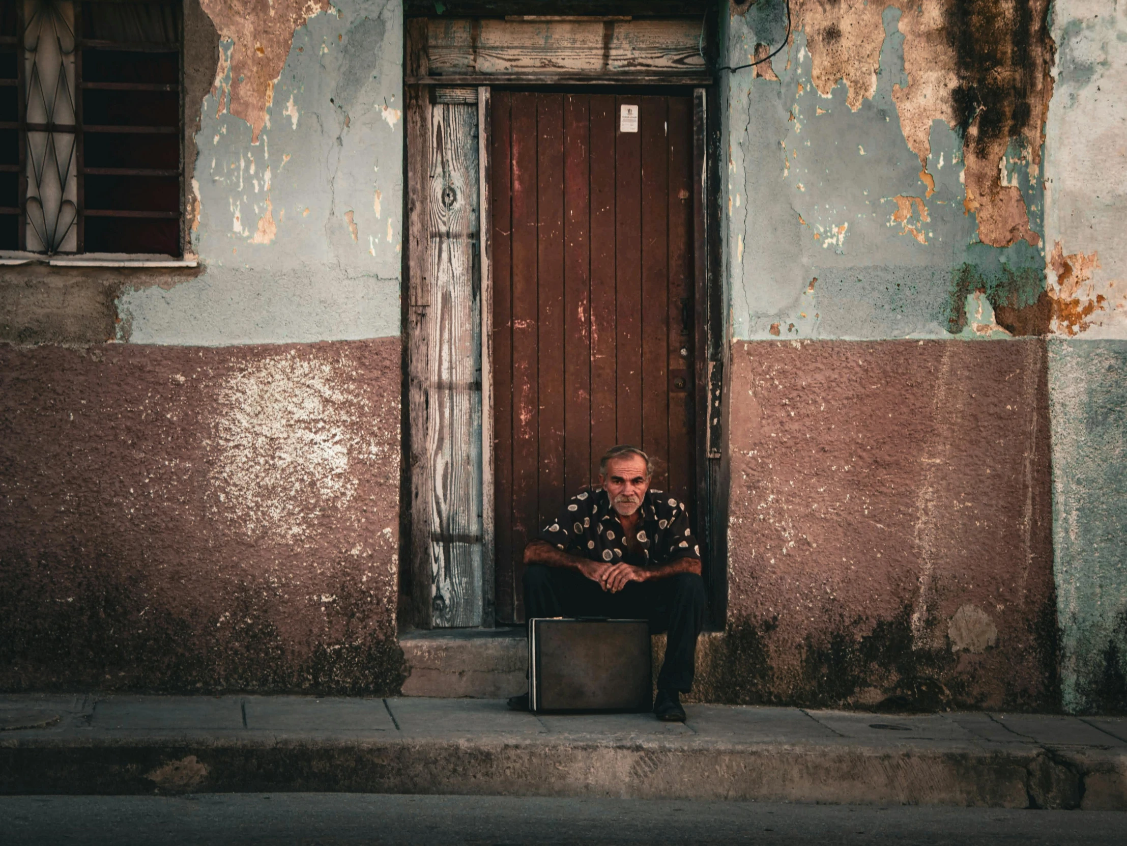 man sitting in doorway of old run down building