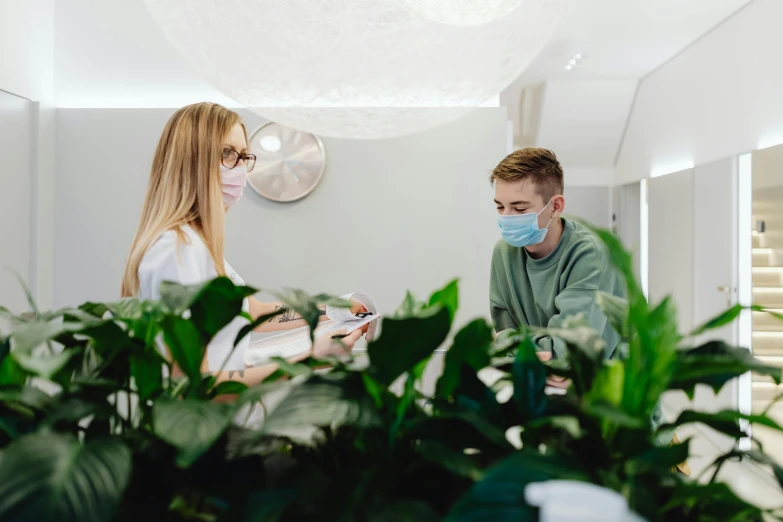 man and woman in protective masks sitting at a counter