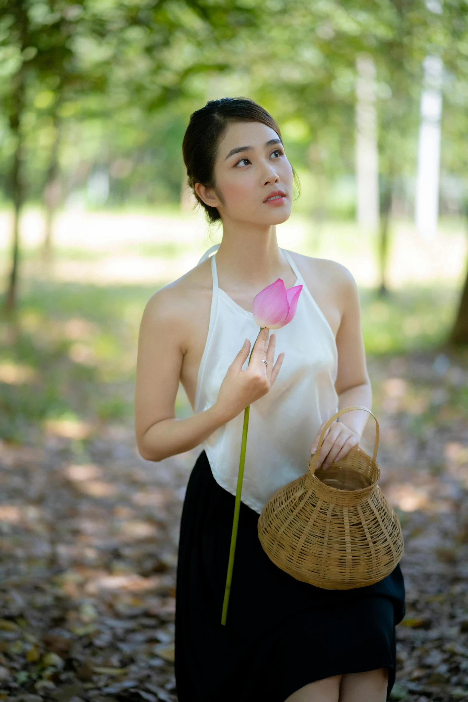 an asian woman in a forest holding a purse and flower