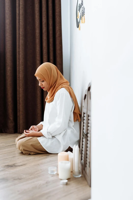 a young woman sitting on the floor with her hands together