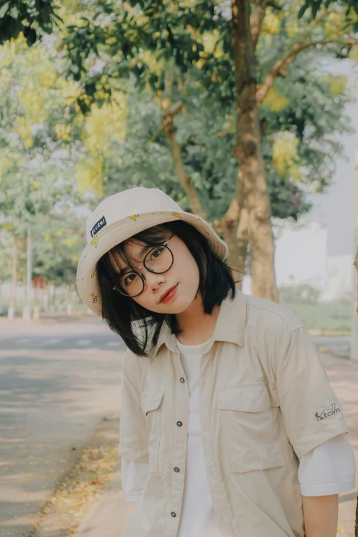 a woman in glasses and a hat next to a tree