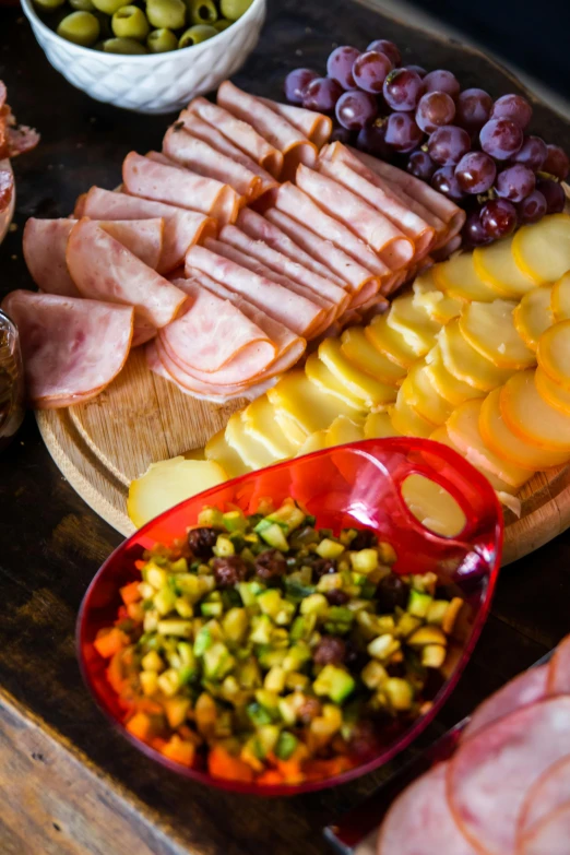 assorted cheeses, meats, fruit and nuts on a tray