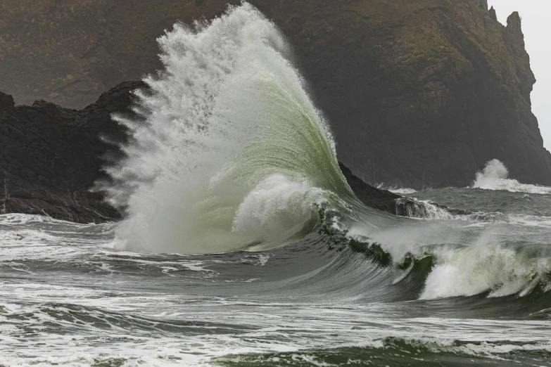 a wave crashes on top of a rock in the ocean