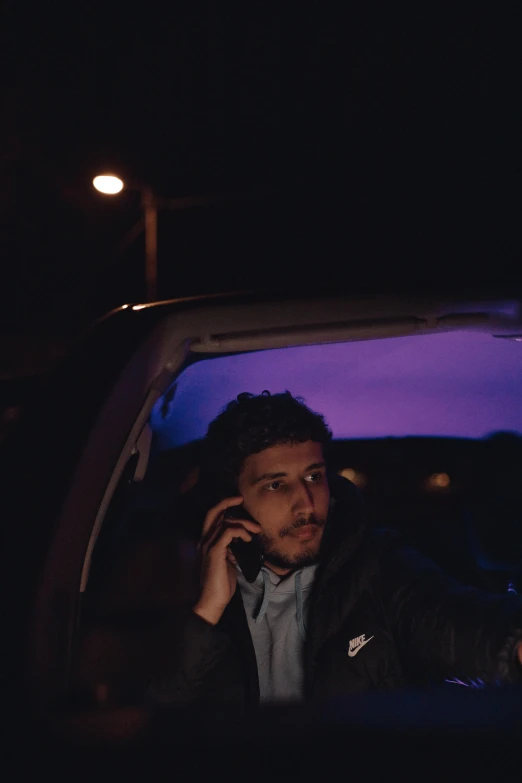 a man sitting in his car talking on a cellphone