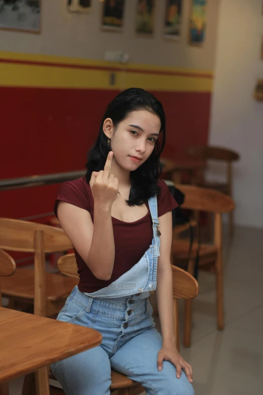 a woman sitting on the lap of a chair, making a finger sign