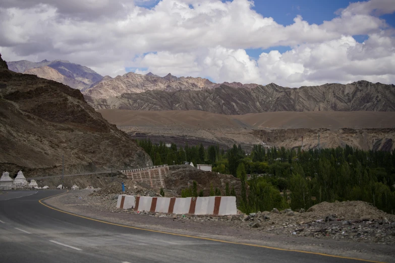 a highway surrounded by rocky mountains and greenery