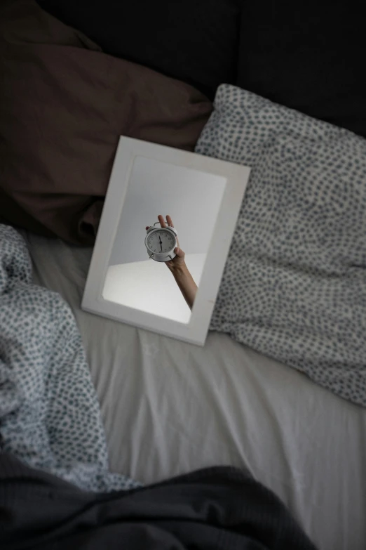 a mirror with a hand holding up a clock