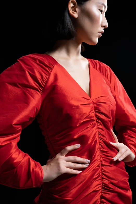 an asian woman in a red top standing with her hands on her stomach