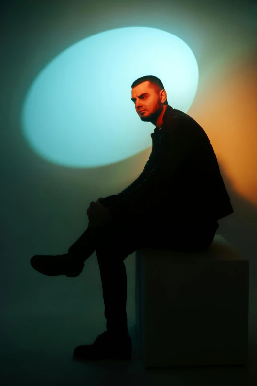 a man in black sitting down in front of a circular area