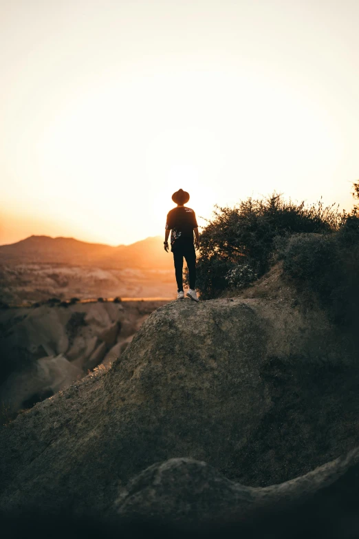 the silhouette of a person standing on a rock