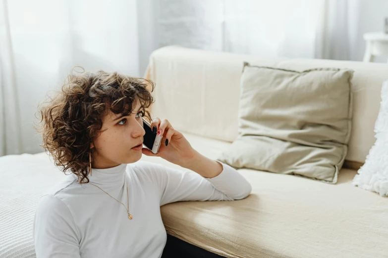 a girl sitting on a couch talking on her phone