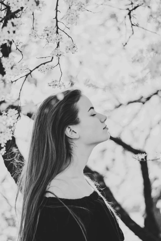 a woman standing under a flowering tree with her eyes closed