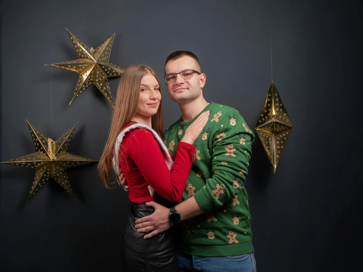 a man and woman posing for a picture under some christmas stars