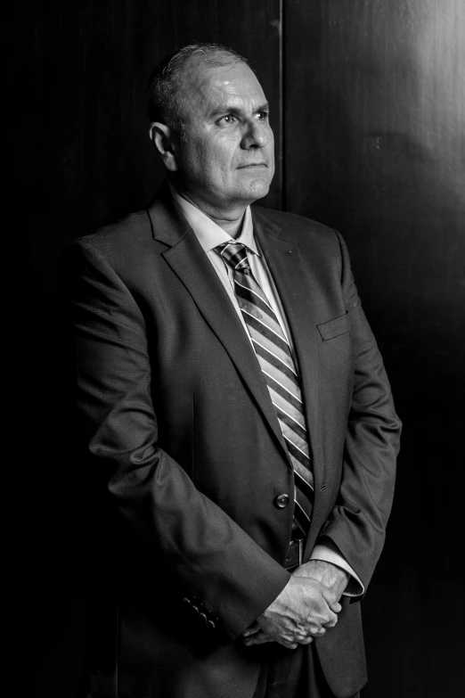 the man stands in front of a wall in a suit and tie