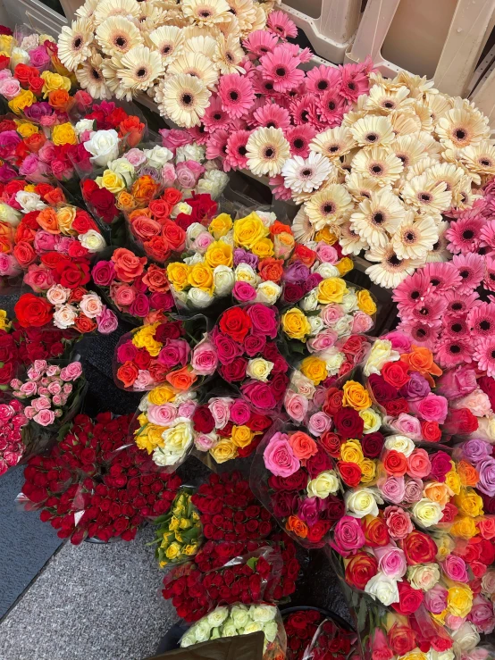 many multicolored flowers are stacked up on display