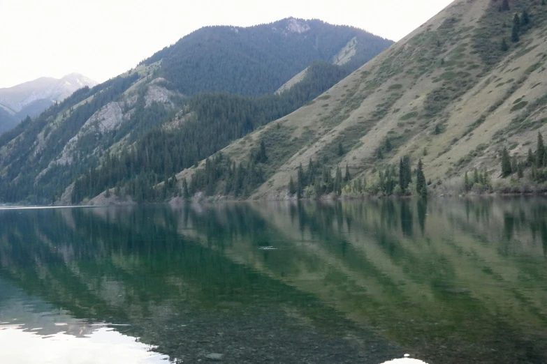 a mountain range next to a lake on a cloudy day