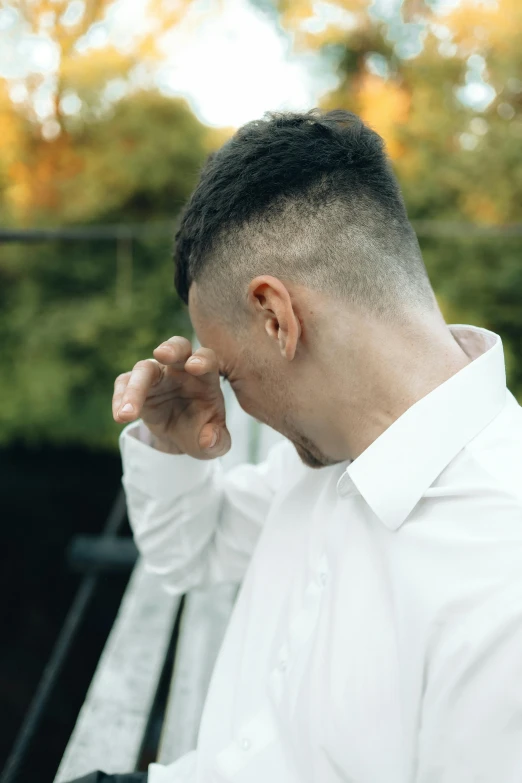 a man sits on a bench, leaning his head to his side and looking away