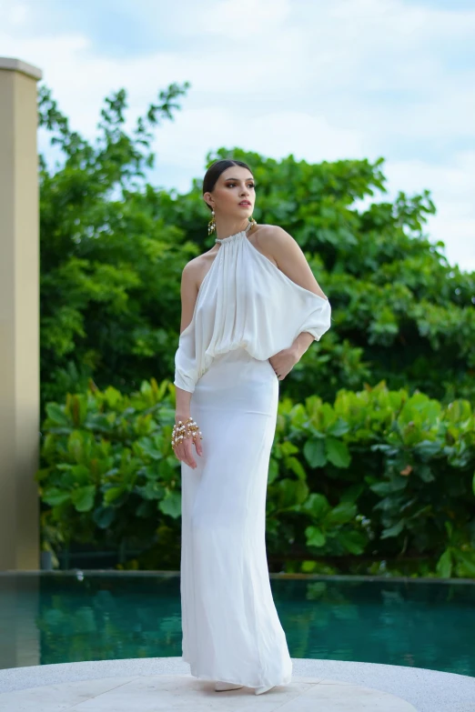 woman in a white long dress standing by a pool