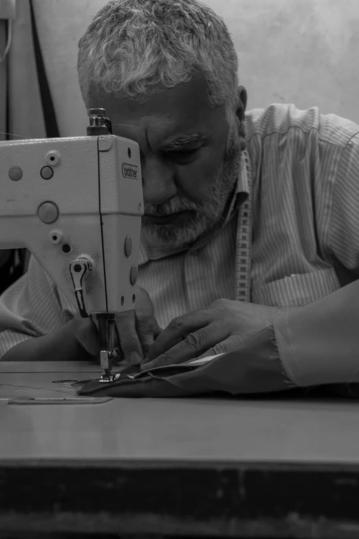an older man uses a sewing machine while sitting