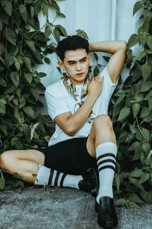 a young man sitting down by some plants