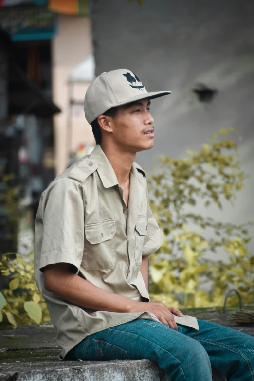 a man is sitting on the cement, wearing a baseball cap