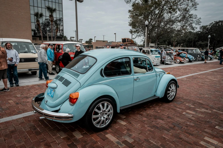 a blue vw bug in the parking lot of a show