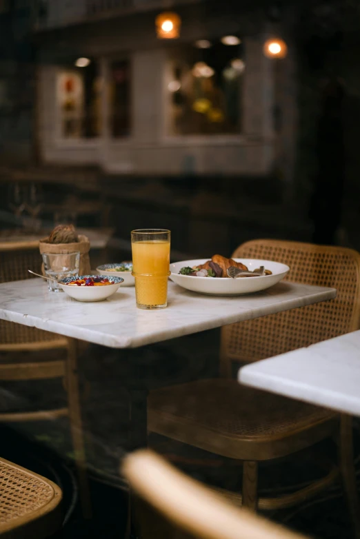 the glass of a beverage sits on the table with two plates of food