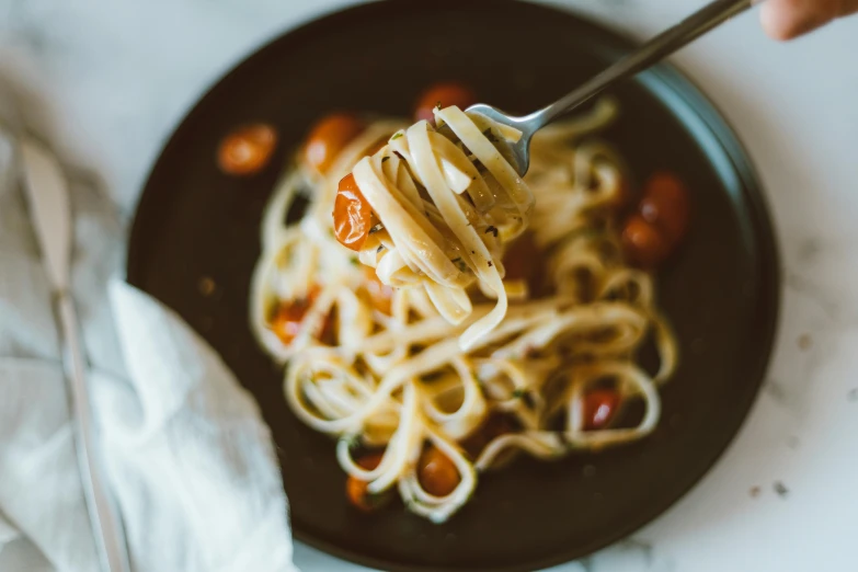 a person is holding a fork full of noodles