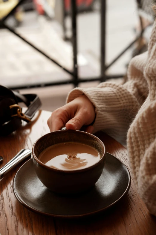 a person's hands on a plate next to a cup of liquid