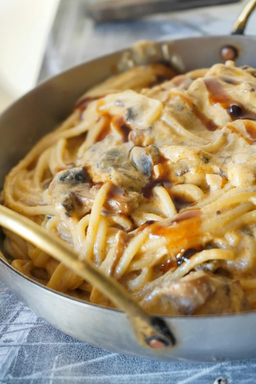 a pan filled with pasta, mushrooms, cheese and bacon