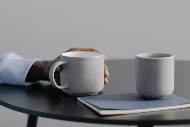 two white mugs sitting on a table with a notepad