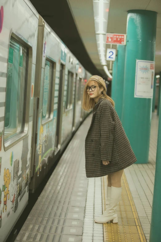 a girl in a long coat at a train station