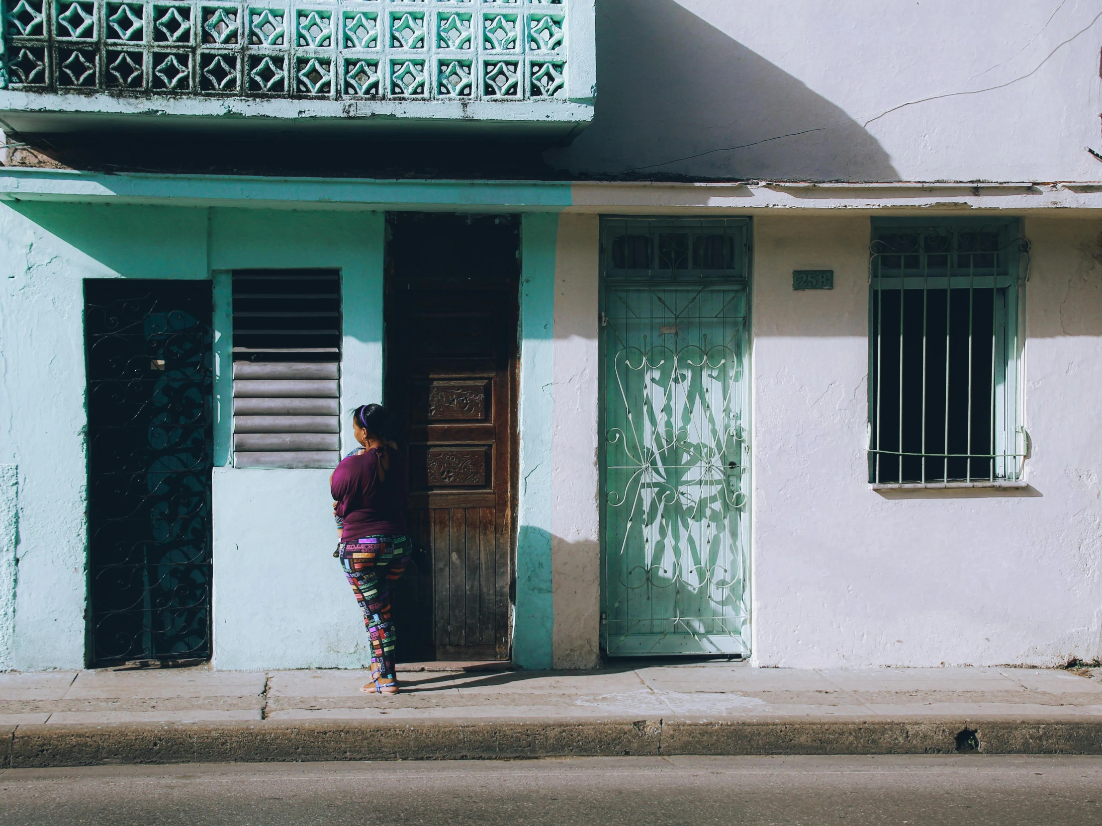 a woman in front of a blue building is leaning out the doorway