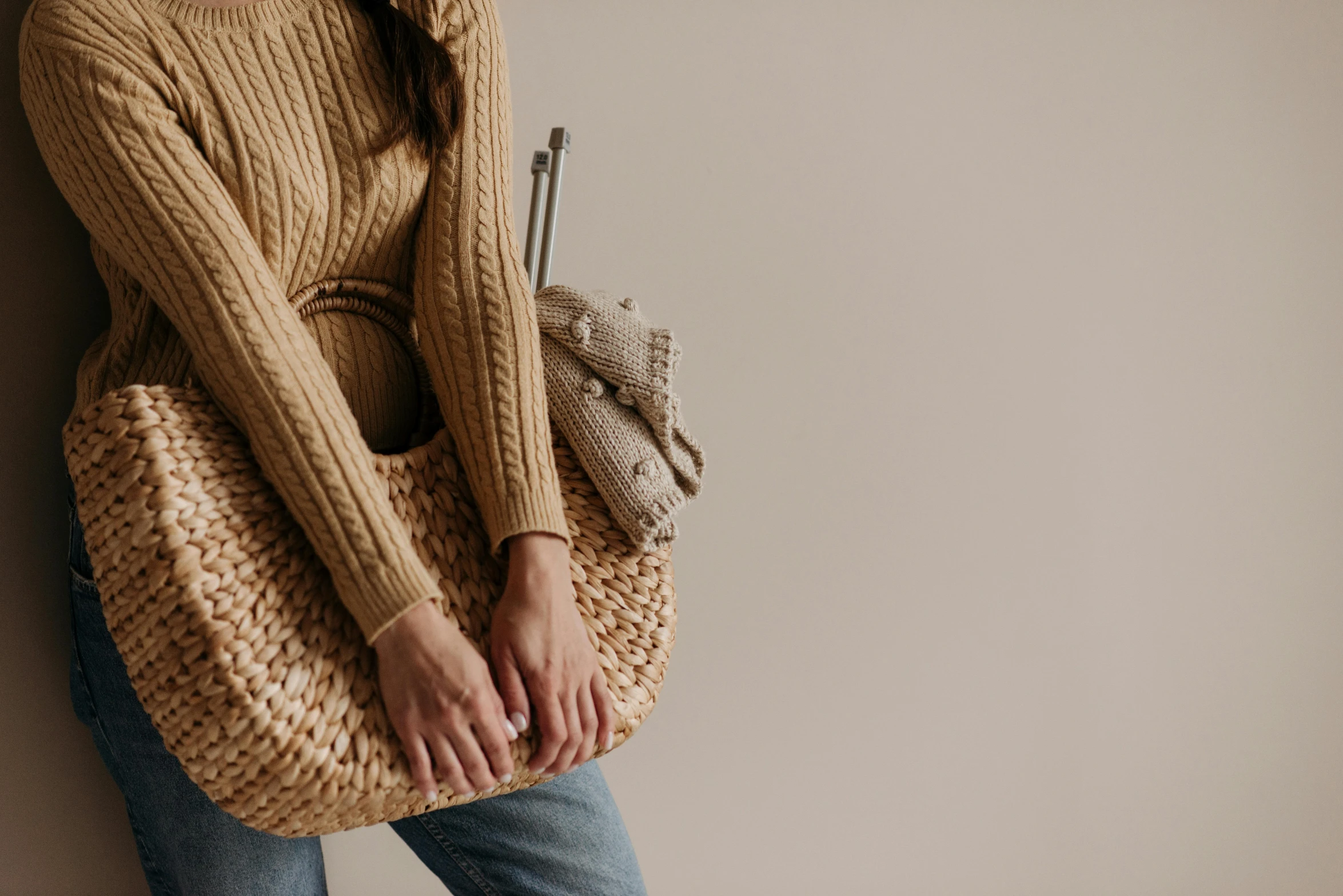 a woman wearing blue jeans and brown sweater carrying a basket bag