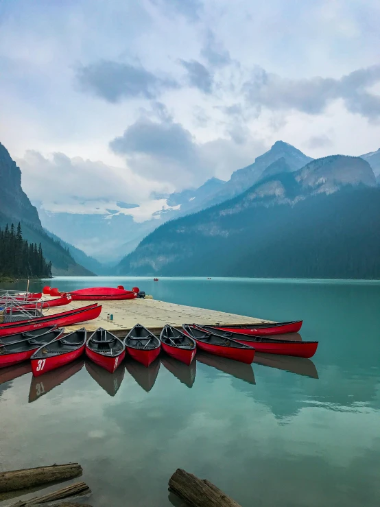 some red canoes are docked up to a dock