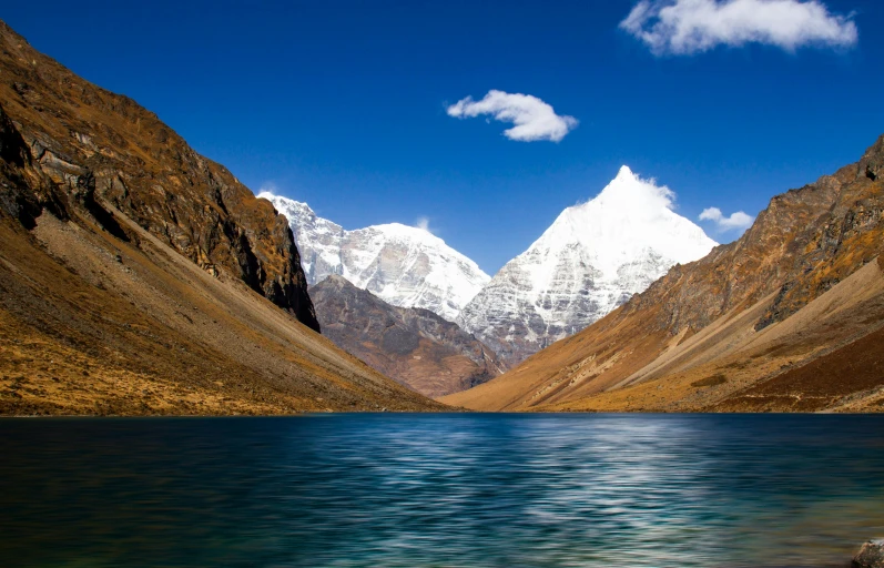 a mountain range looms over the river as it crosses through the valley