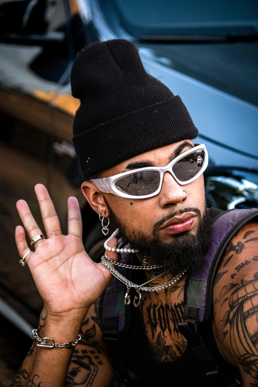 a bearded man with chains on his neck and sunglasses over his mouth