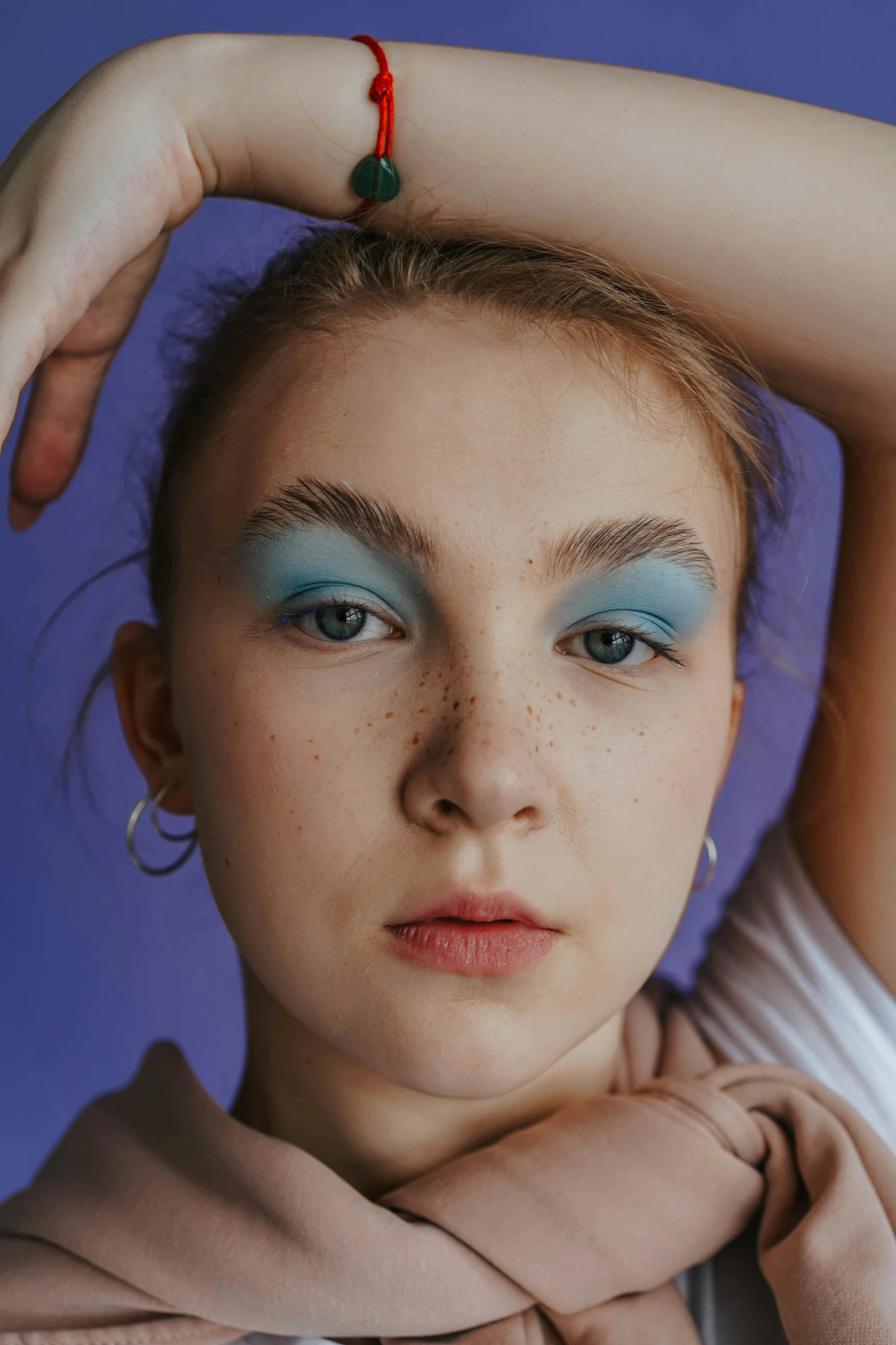 woman in a scarf has bright blue makeup and red and green accessories