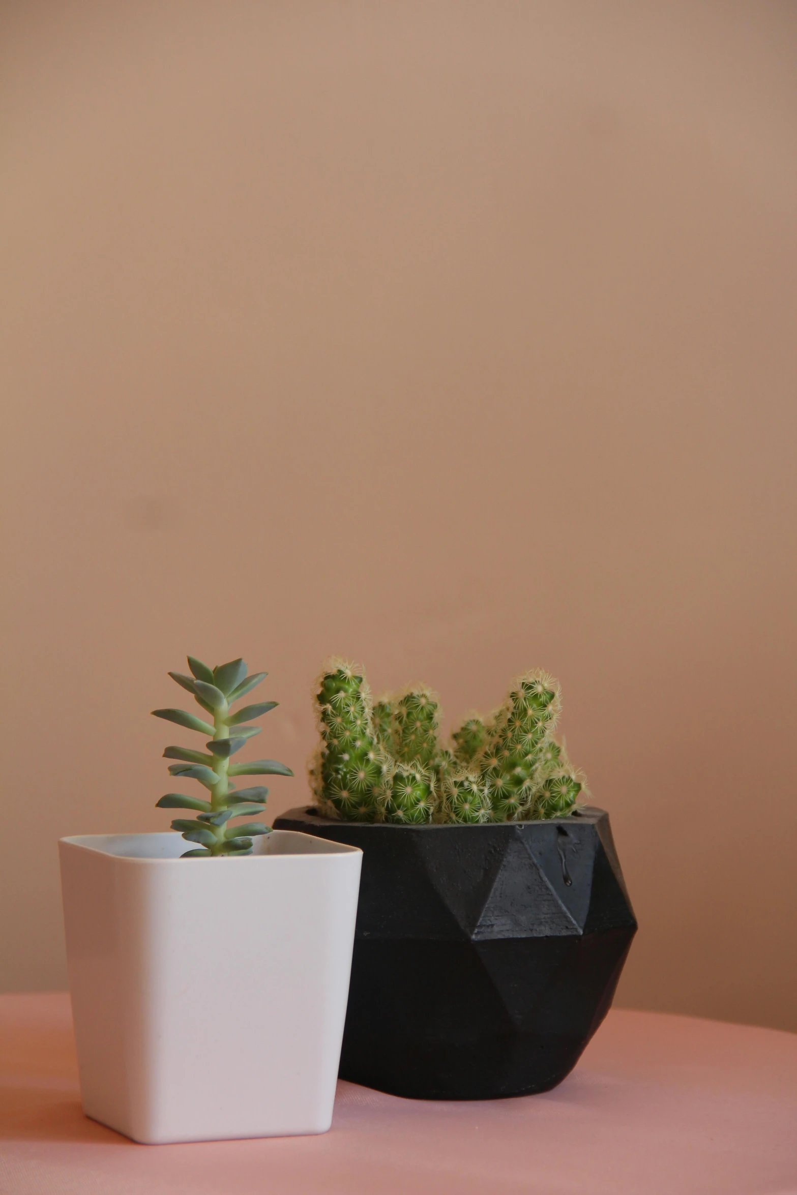 two pots are on a pink table next to each other