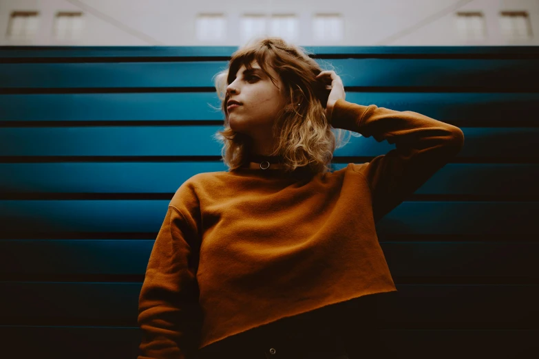 a young woman is looking upward while wearing an orange sweater