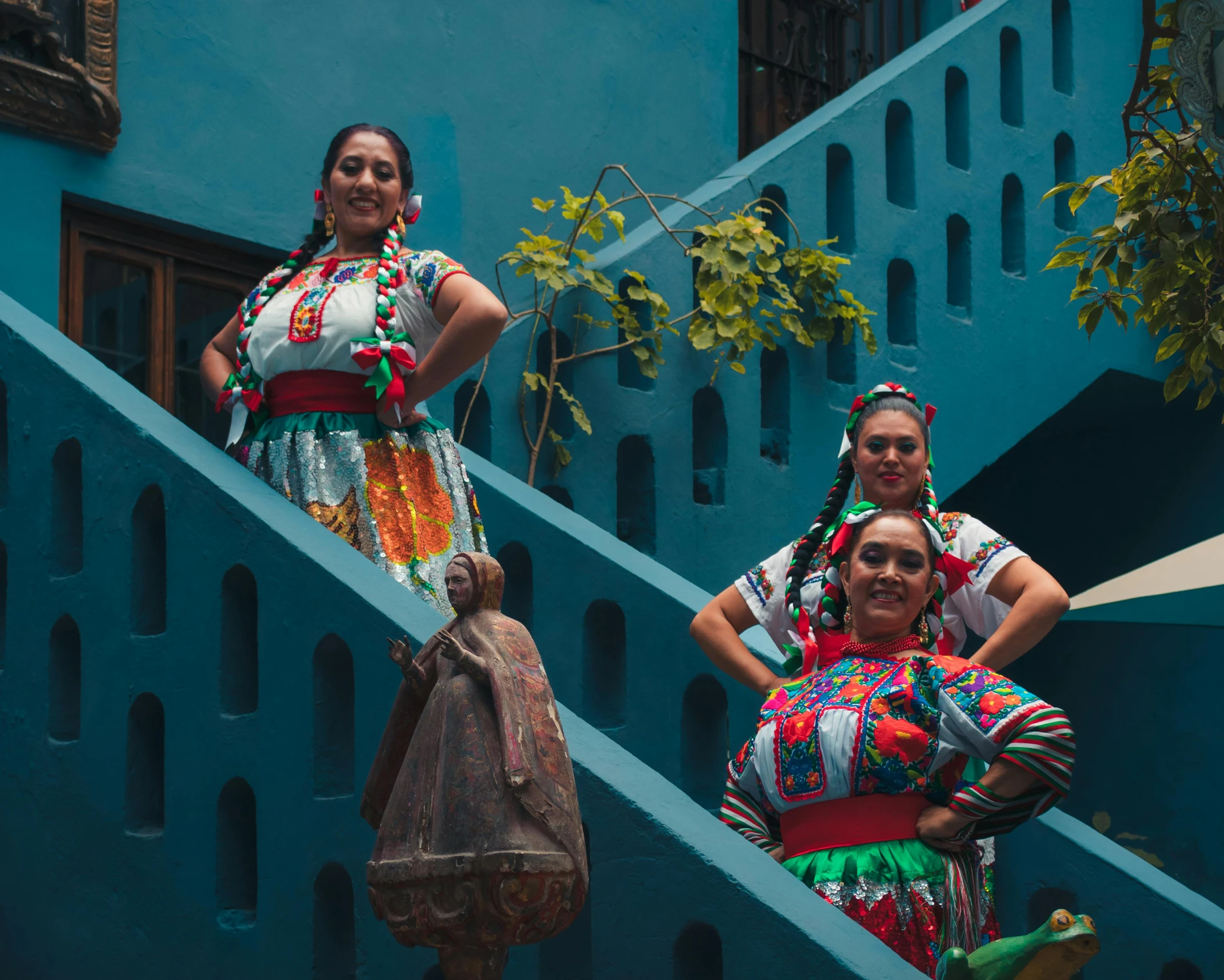 three women wearing brightly colored clothing, standing on steps