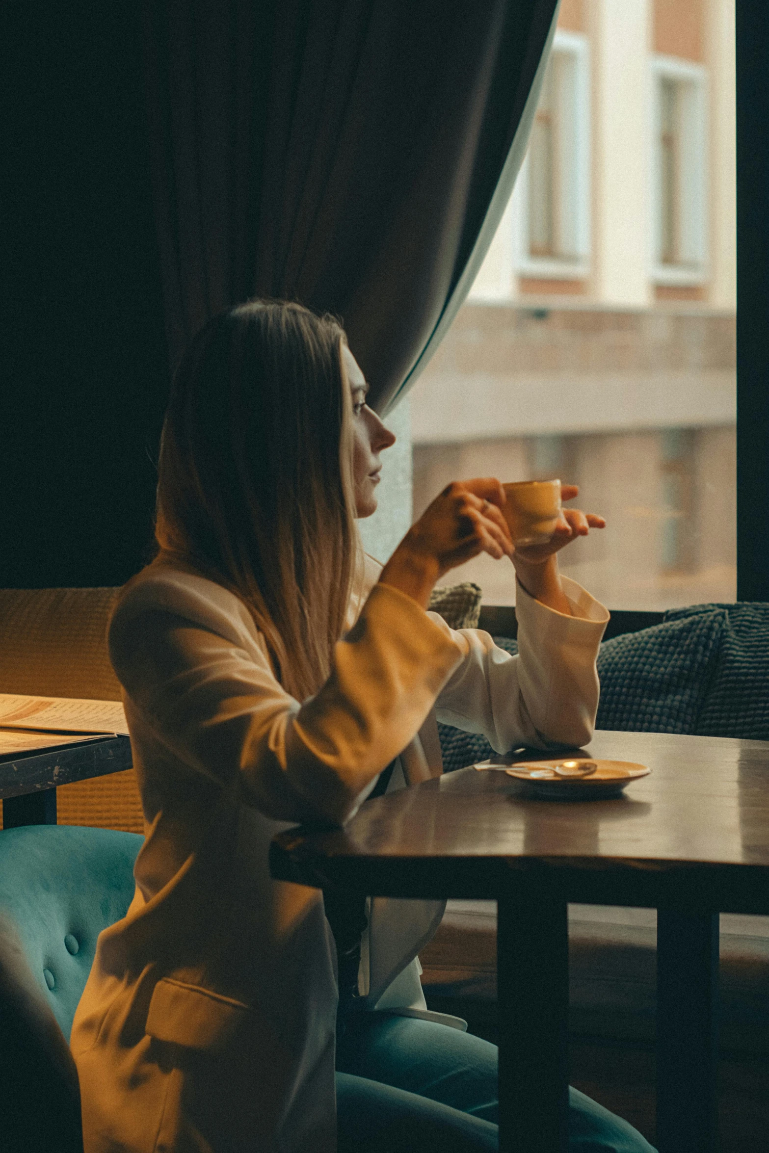 a girl is sitting at the table eating with a glass of tea