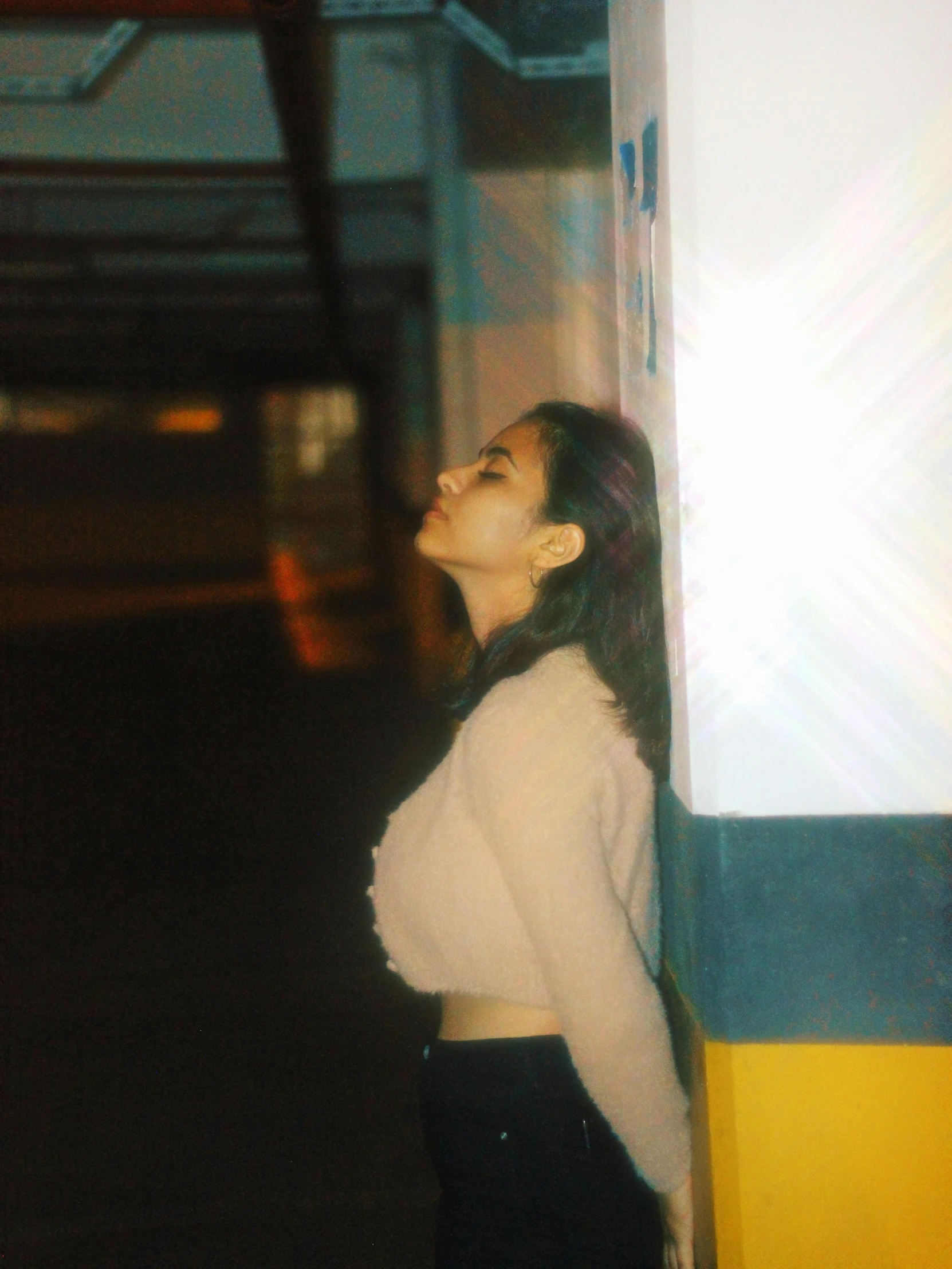 a girl standing against a wall next to a parking meter