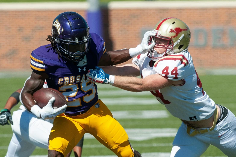 a football player is trying to keep the ball from being tackled by a receiver