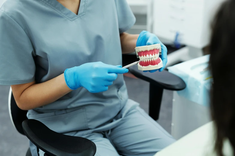 a person wearing blue gloves holding a small toothbrush