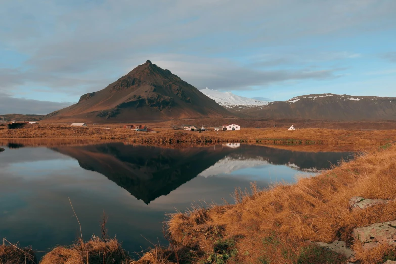 a lake and mountains near a grassy bank