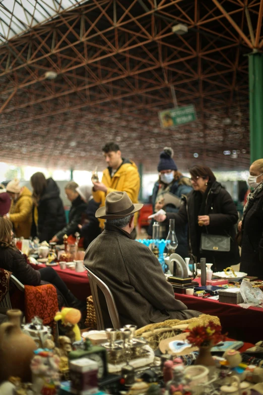 people sitting in front of tables at an indoor market
