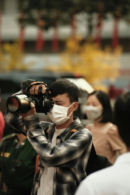 a man holding a camera wearing a mask
