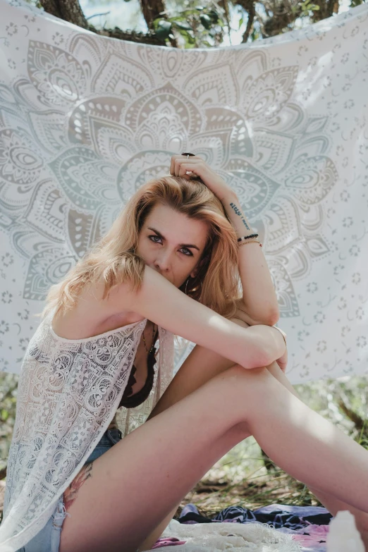 a young woman sits under a sheet in the shade